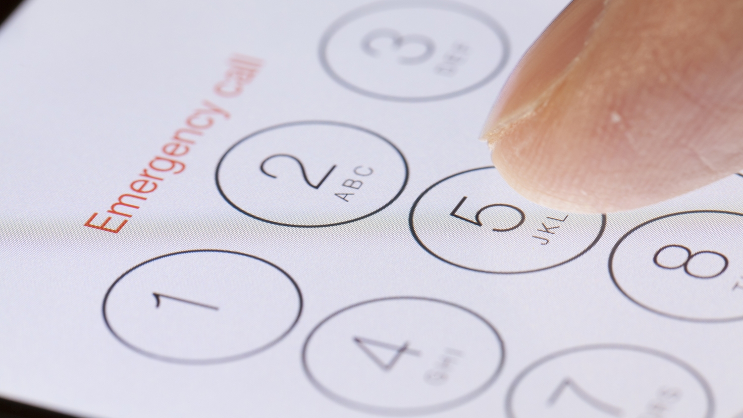 A close up of a person's finger about to touch an iPhone screen, which is showing an 'emergency call' message