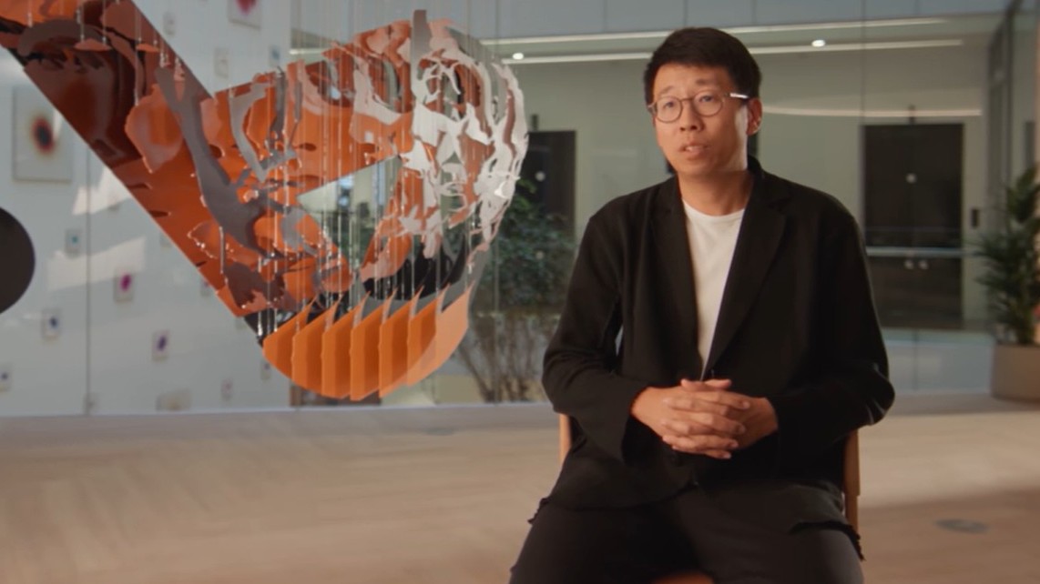 A medium shot of Jack Zhang sitting in a chair in the Airwallex office.
