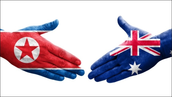 Two hands about to shake, one bearing the North Korean flag, the other the Australian flag.