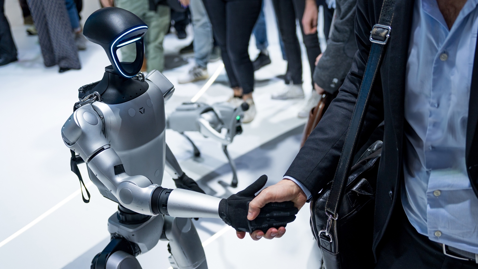 A close up of a humanoid robot shaking hands with a man in business attire.
