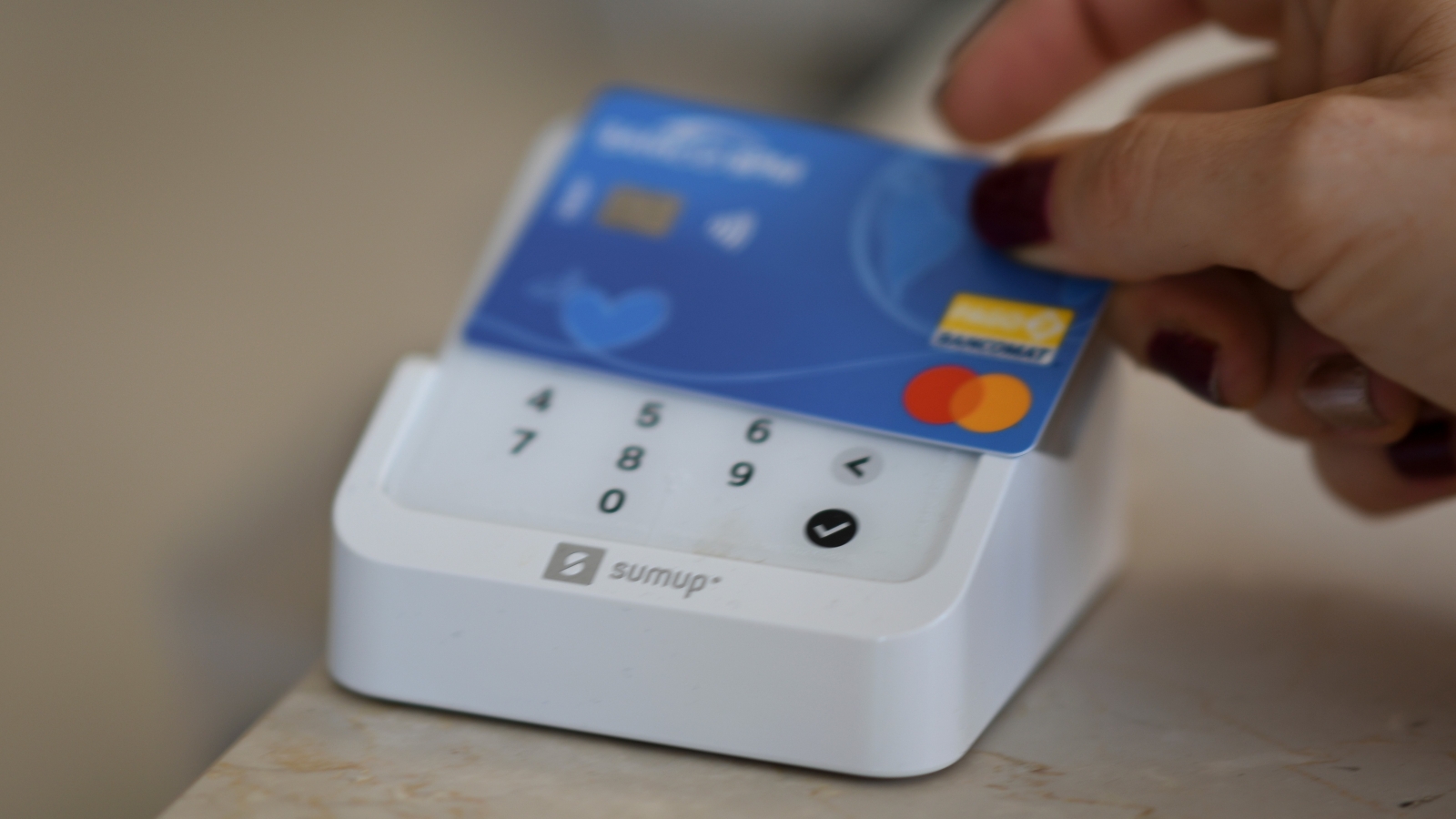 A close up of an EFTPOS terminal on which someone is tapping a Mastercard card.