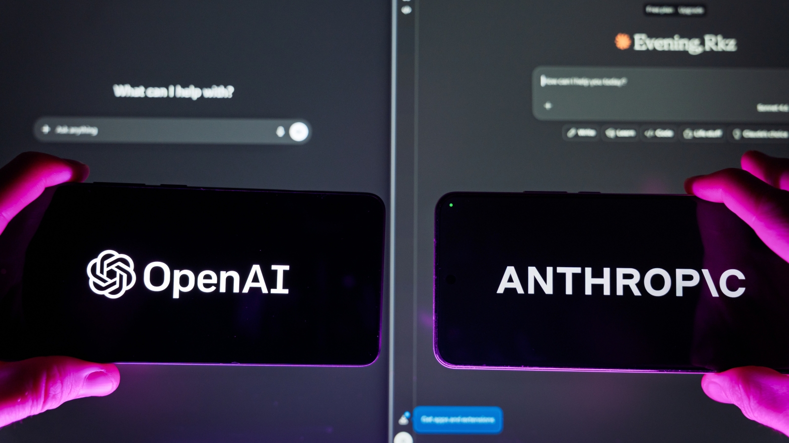 A closeup of hands holding two smartphones, one displaying the OpenAI logo, the other the Anthropic logo.