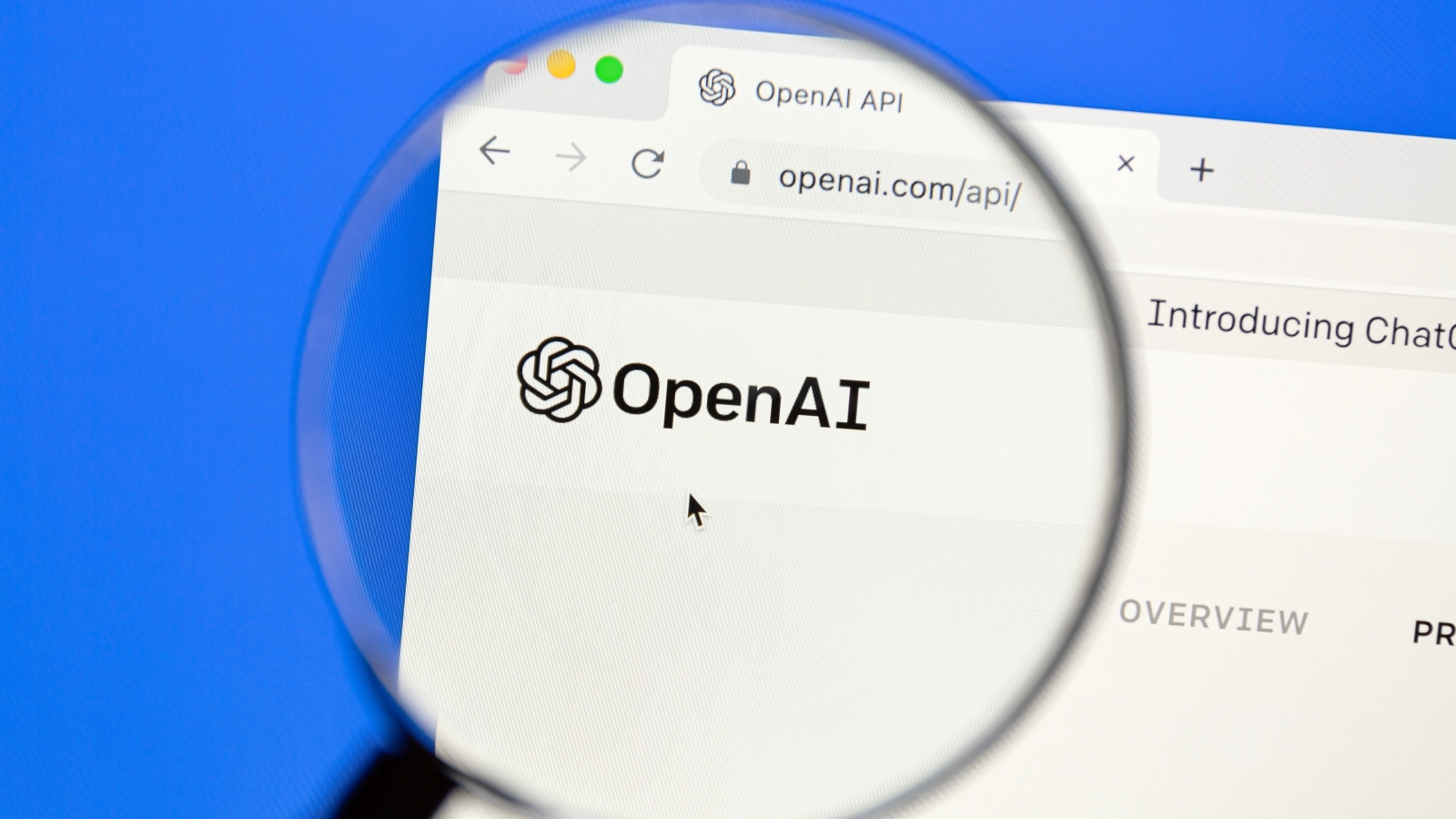 A close up of a magnifying glass being held over the OpenAI logo on its website.