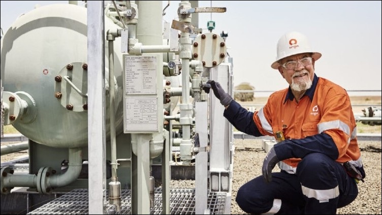 Origin worker crouching down next to some machinery.