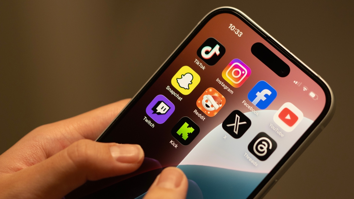 A close up of an iPhone displaying 10 social media apps, each of which has been designated under Australia's under-16s social media ban.