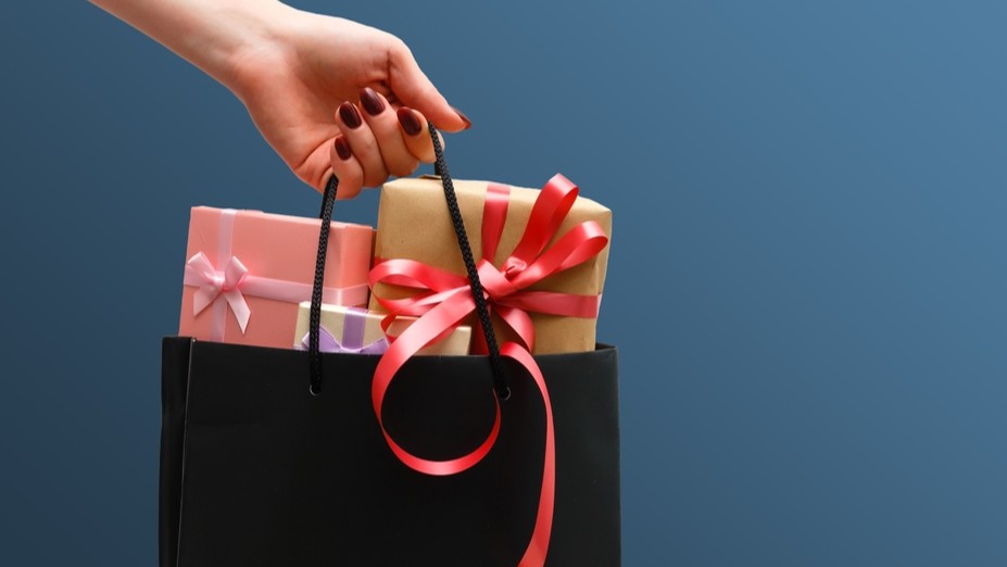 A hand holding a bag of gift boxes.