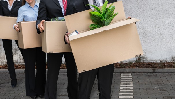 Fired employees walking away with their belongings in boxes.