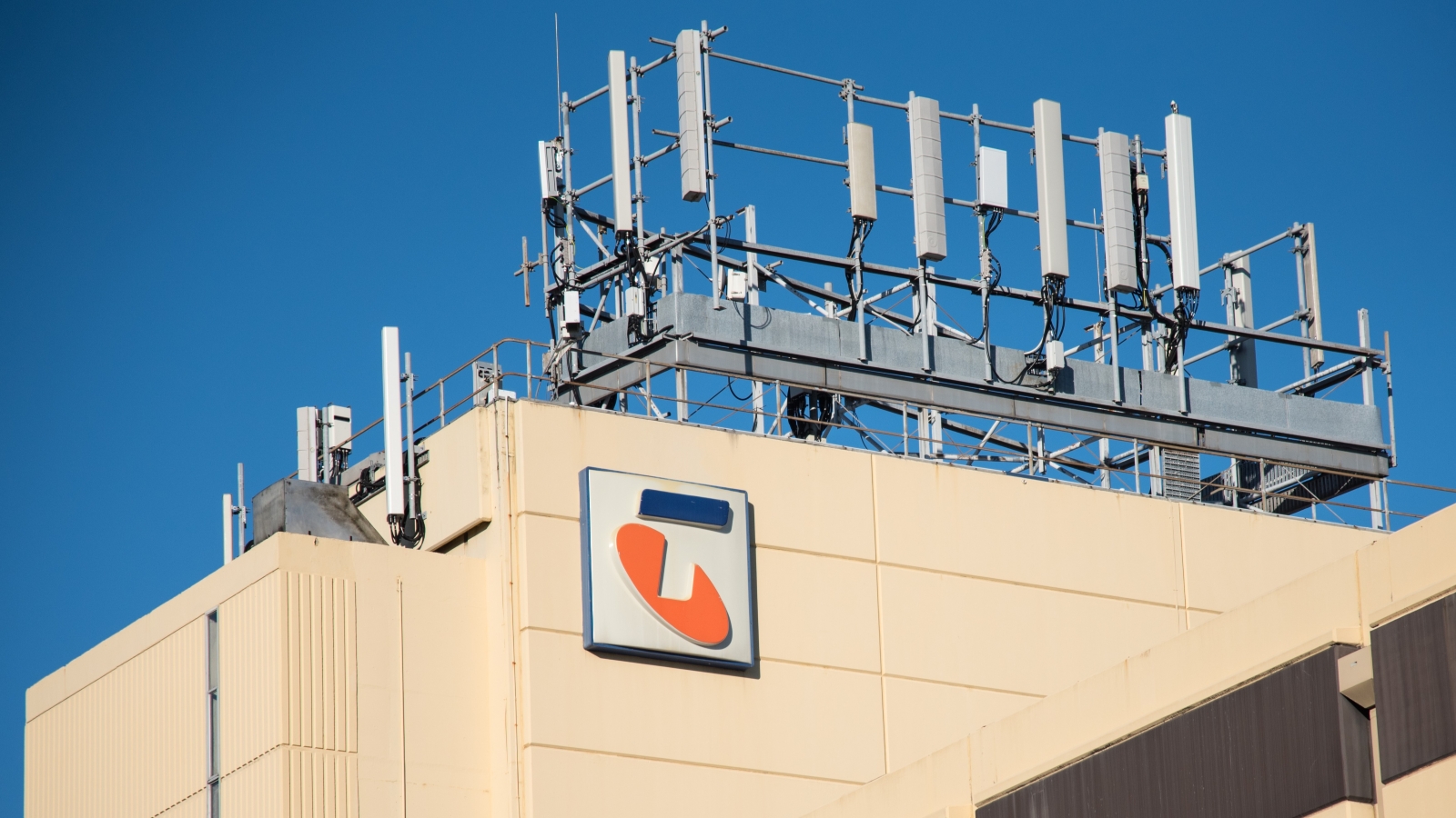 A close up of an office building with the Telstra logo and cellular network devices on its roof.