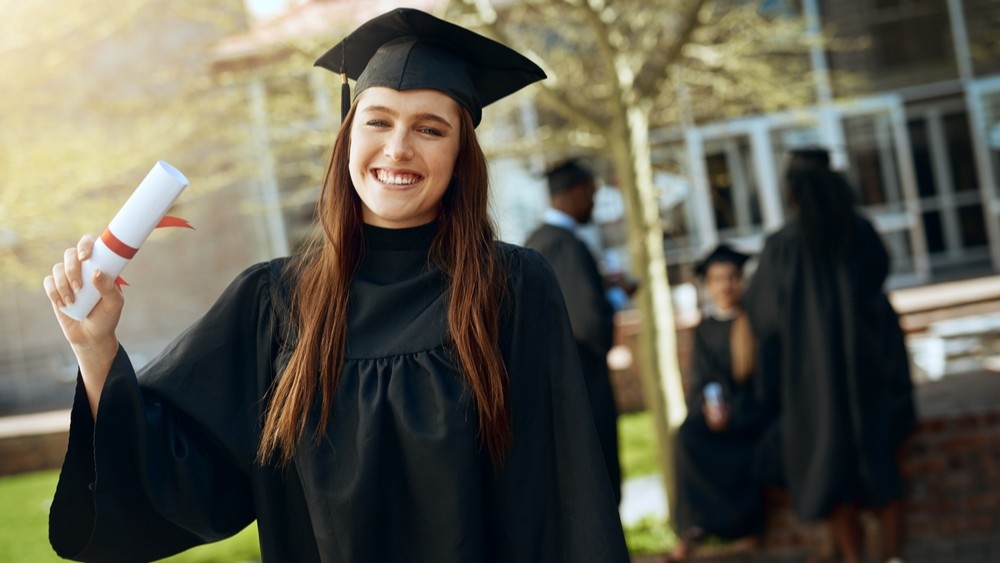 Smiling woman holding uni degree.
