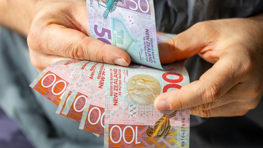 Person's hands holding New Zealand money.