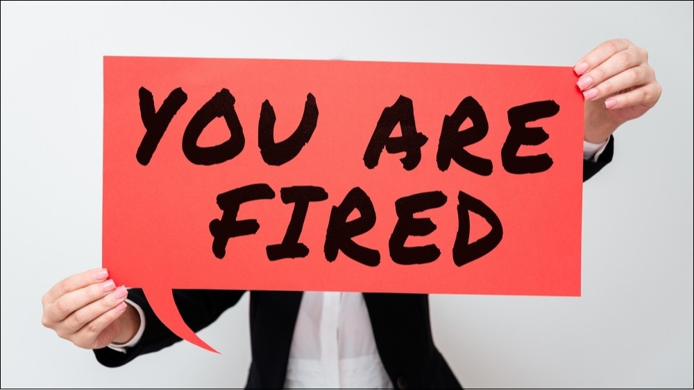 Someone holding up a giant red sign saying YOU ARE FIRED.