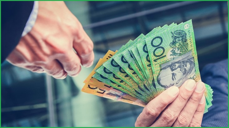 Businessman handing over a handful of Australian money